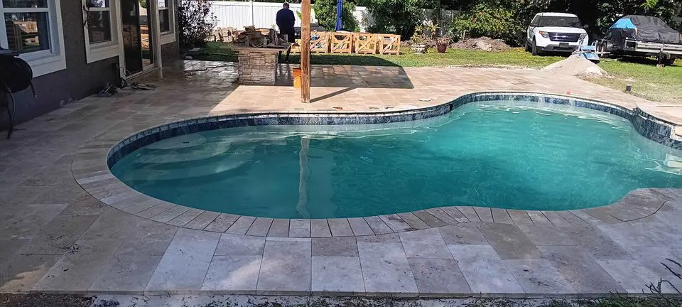 A pool with a natural stone pool deck, paved in travertine pavers at a home in West Palm Beach FL