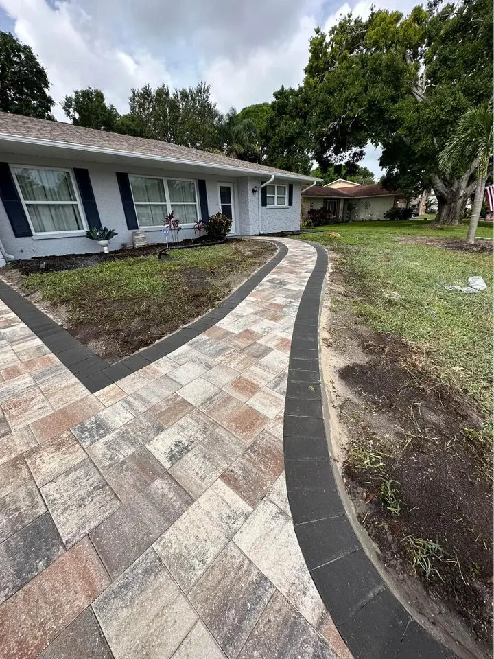 A paver walkway installed in front of a home with marble pavers and concrete paver border